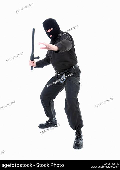 Anti-terrorist police guy wearing black uniform and black mask holding firmly police club in one hand ready for action, shot on white