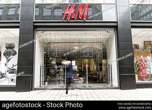 01 April 2020, Hamburg: A man walks in front of the closed entrance of a department store of the fashion chain H&M in downtown Hamburg