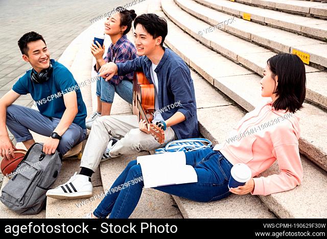 The young college students sat on the steps to play guitar