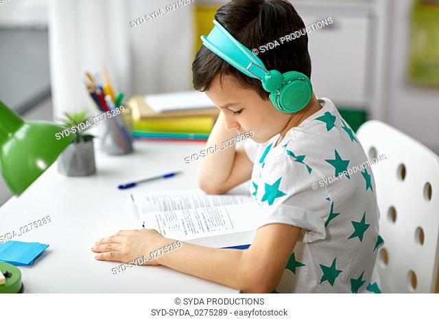 boy in headphones with textbook learning at home