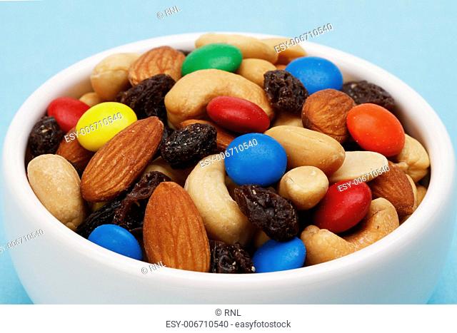 Macro shot of trail mix in a white bowl against a blue background