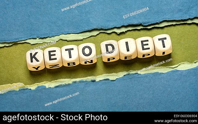 keto diet word abstract in wooden letter cubes against paper abstract in green and blue tones, healthy ketogenic diet with high fats and low carbs