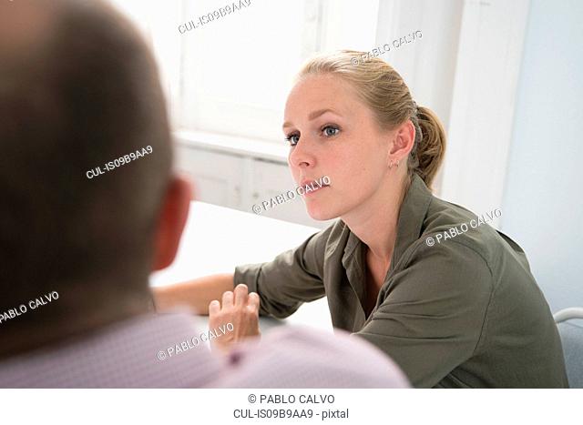 Over shoulder view of young businesswoman having meeting at office desk