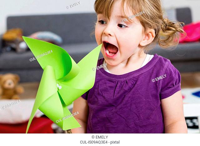 Girl excited over paper windmill at home