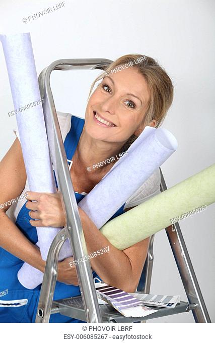 Woman holding numerous wallpaper rolls