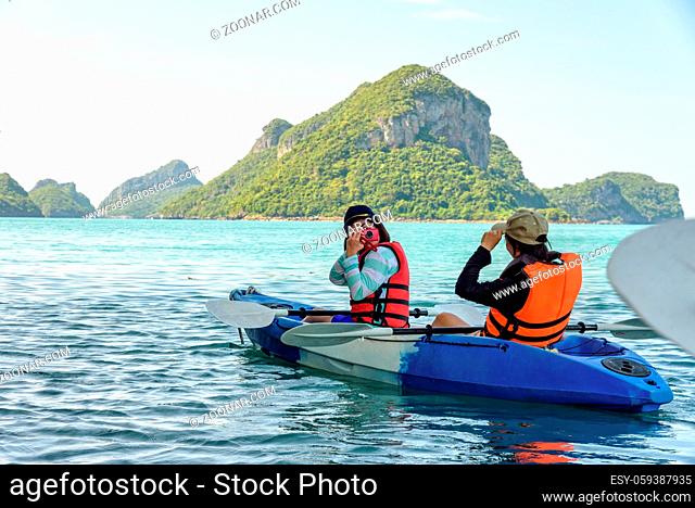 Two women are mother and daughter using a camera take pictures on kayak while travel by boat with happy on the sea during summer at Ko Wua Ta lap islands in Mu...