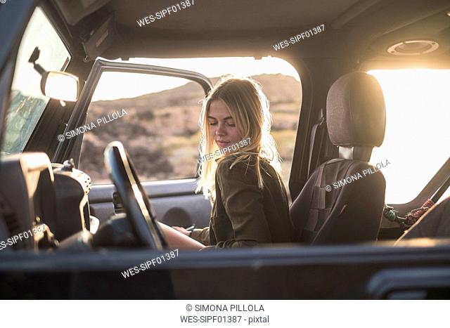 Woman sitting in car at sunset