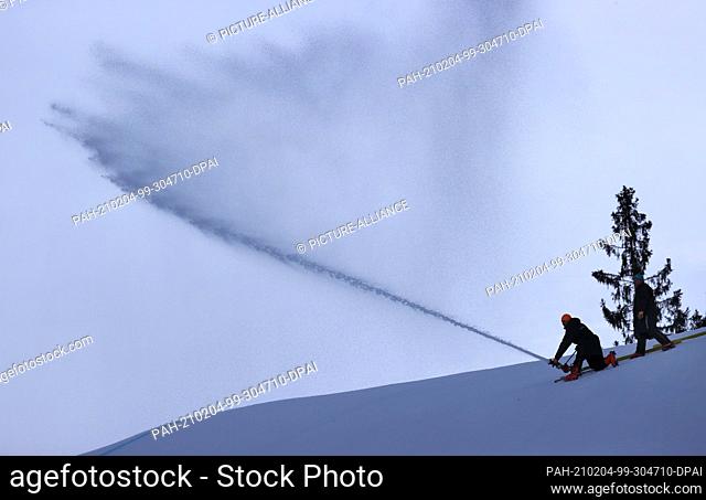 04 February 2021, Bavaria, Garmisch-Partenkirchen: Alpine skiing: World Cup, downhill, men: Helpers prepare the Kandahar downhill with water to freeze the snow
