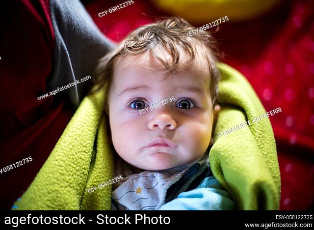 portrait of 5 month old baby wrapped in blanket in mother's arms