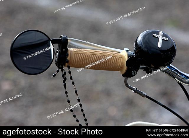 15 October 2023, Saxony-Anhalt, Oschersleben: A bicycle bell with a cross is attached to the steering wheel of a moped at the biker service