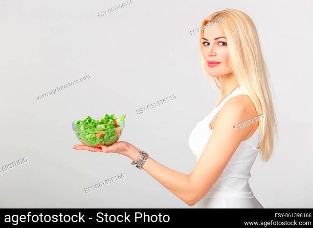 beautiful smiling blond woman in white dress with fresh salad. diet