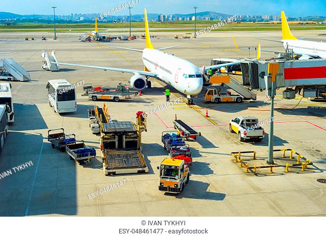 Passengers leaving plane, service buses, gangway, luggage transporters at runway in bright sunshine, Istanbul airport, Turkey