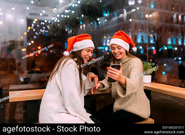 Two young girls wearing female and using smartphone at the cafe