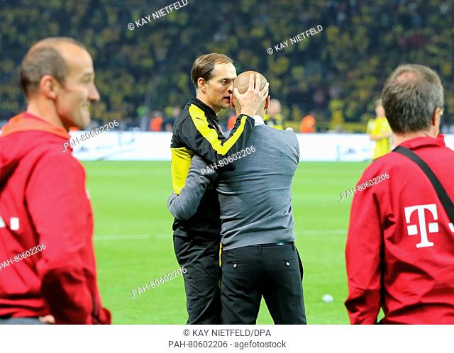 Dortmund's head coach Thomas Tuchel (C-L) embraces his Munich counterpart Josep 'Pep' Guardiola after the German DFB Cup final soccer match between Bayern...