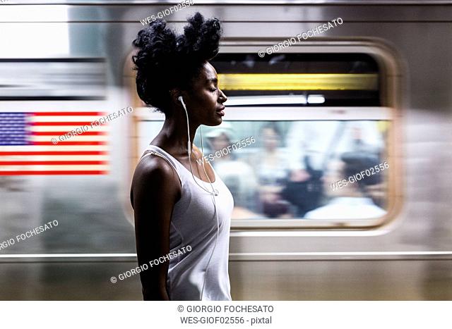 USA, New York City, Manhattan, woman with earphones on subway station platform