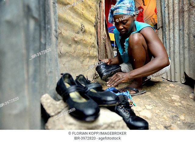 Woman shining the shoes of her children for their first day of school, Camp Icare for earthquake refugees, Fort National, Port-au-Prince, Haiti