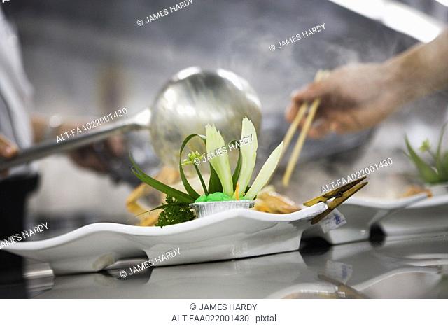 Chefs dressing plates in commercial kitchen