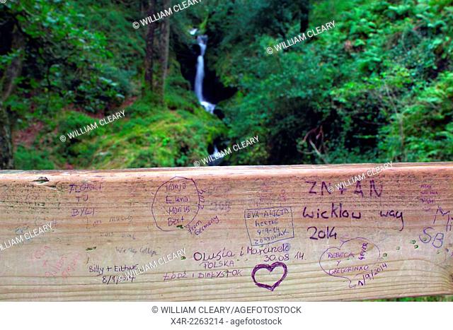 Railing inscribed with names of visitors and lovers with Poulanass waterfall in the background, Glendalough, County Wicklow, Ireland