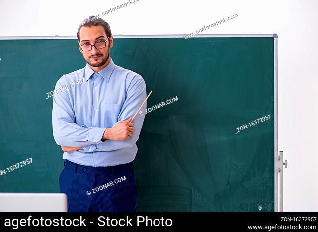 Young teacher in the classroom in front of green board