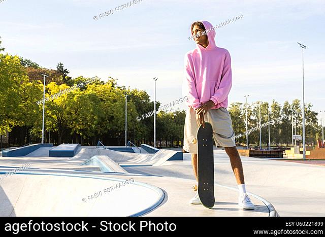 Stylish cool teen male skateboarder at skate park