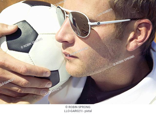Man in a White Suit and Sunglasses Holding a Soccer Ball on His Shoulder  Namibia
