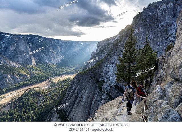 Group of hikers going down to Yosemite Point with the amazing view of the valley and the sunset, California, USA