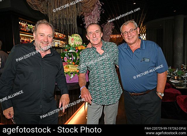 28 July 2022, Bavaria, Munich: Musicians Harold Faltermeyer (f-l), Stefan Zauner and Ralf Faltermeyer smile before the wine tasting at the WACA restaurant at...