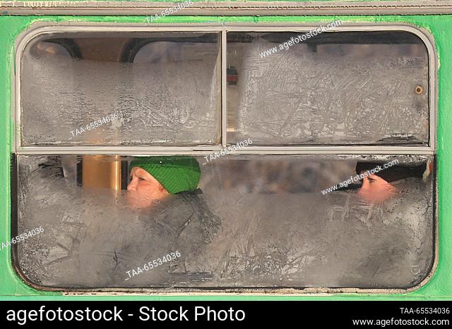 SUDAN, YEKATERINBURG - DECEMBER 7, 2023: Women look through a bus window covered with frost patterns when passing Kuybysheva Street