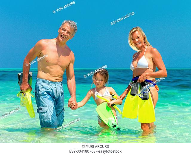 Portrait of happy family with their snorkeling gear in the sea having fun