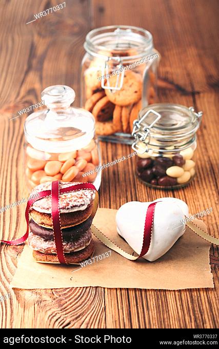 Gingerbread cookies, candies, cakes, sweets in jars on wooden table. Portrait orientation