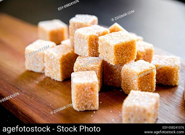 Brown cane sugar cubes on a wooden cutting board