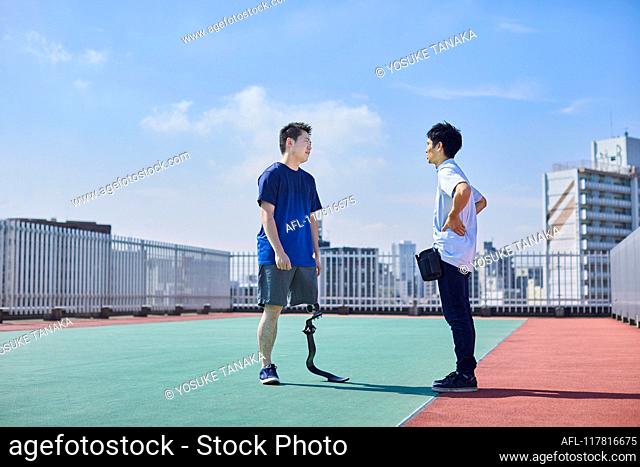 Japanese prosthetist working with amputee on rooftop
