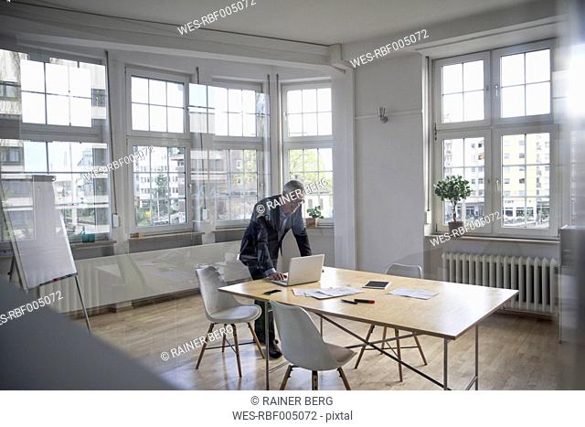 Mature businessman using laptop on boardroom table