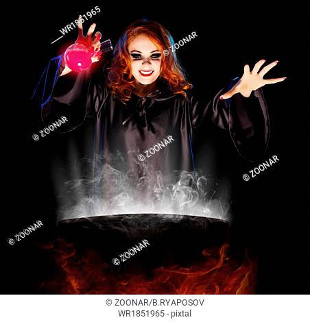 Young witch with potion and cauldron isolated