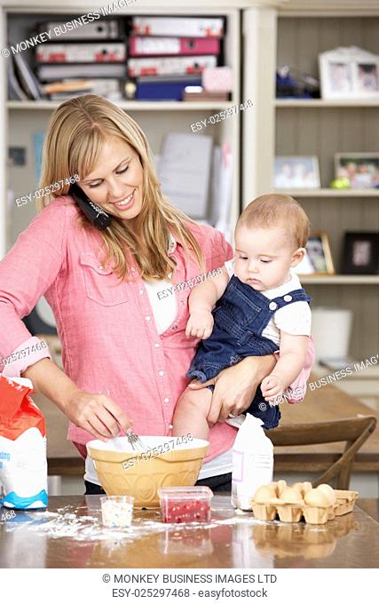 Mother And Baby Daughter Preparing Ingredients To Bake Cakes In Kitchen