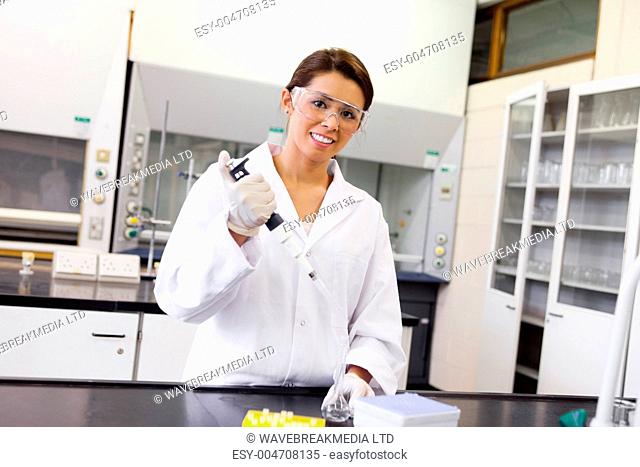 Smiling scientist pouring a liquid in an Erlenmeyer flask