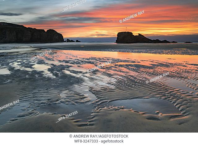 Sand ripples captured at sunrise on the beach at Perranporth on the north coast of Cornwall, with Chapel Rock in the distance