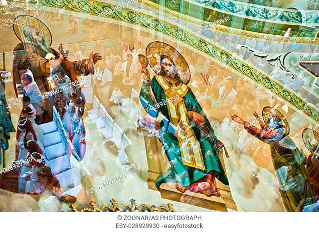 Mukyluntsi , Ukraine - 26 june, 2016: First holy communion. Multiexposition of people in church and wall painting with Jesus