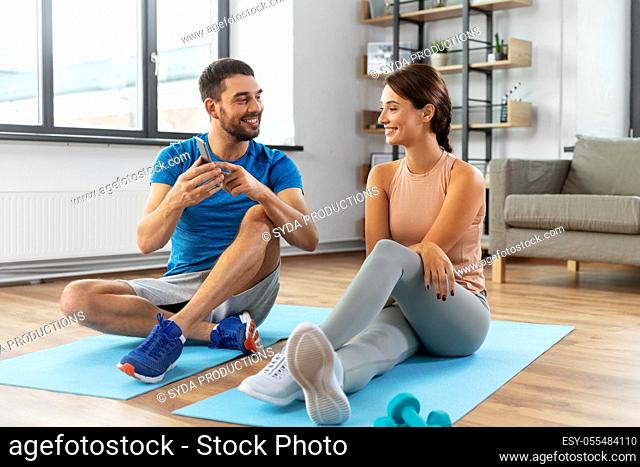 happy couple with smartphone doing sports at home
