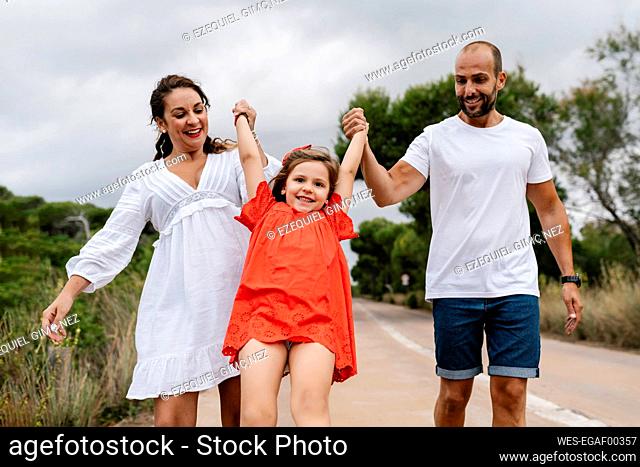 Happy parents lifting up daughter at countryside