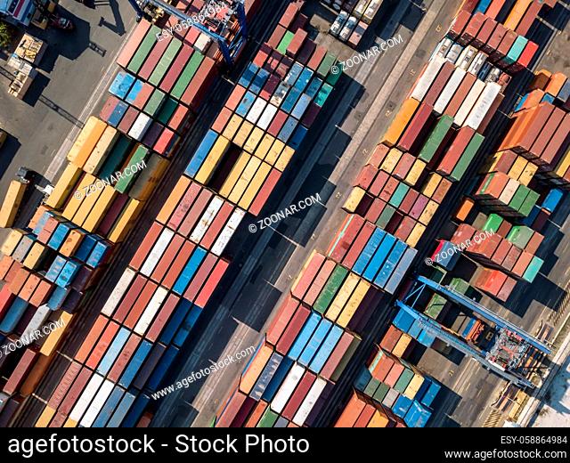 Panoramic view at the warehouse with many multicolored containers. There are cranes and trucks. Horizontal photo. Outdoors