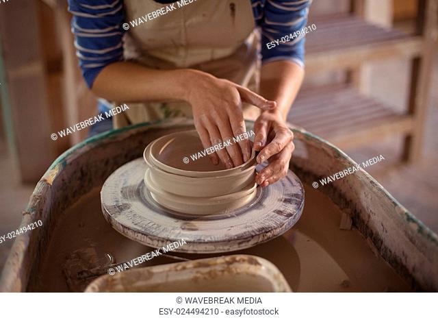 Mid section of female potter making pot