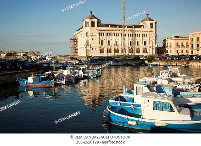 Fishing boats inside the harbor with the Post Office building at the background, Ortigia island, Syracuse, Sicily, Italy, Europe