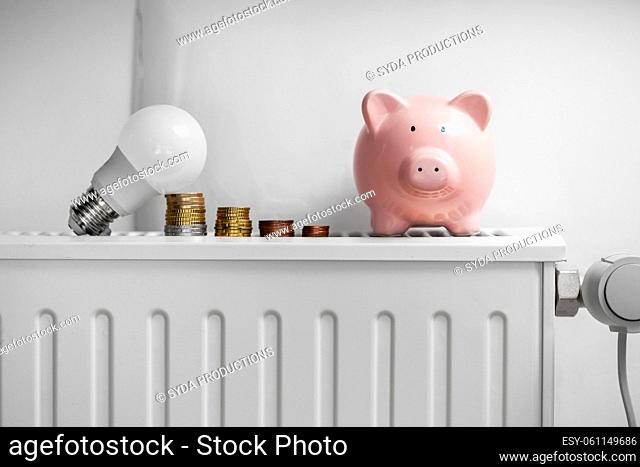 piggy bank, light bulb and coins on radiator