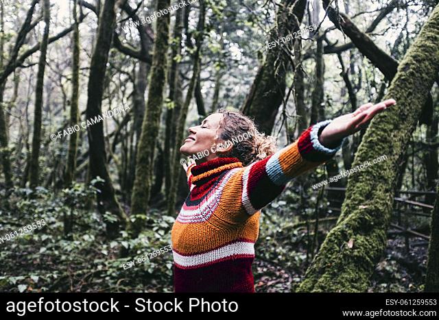 Happy adult woman smile and open arms to embrace beautiful nature forest around her. Concept of green ambient and sustainable tourism travel people