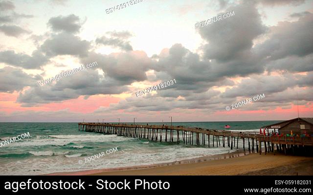 old wooden pier on the Atlantic coast at sunset under a pink sky on the Outer Banks of North Carolina