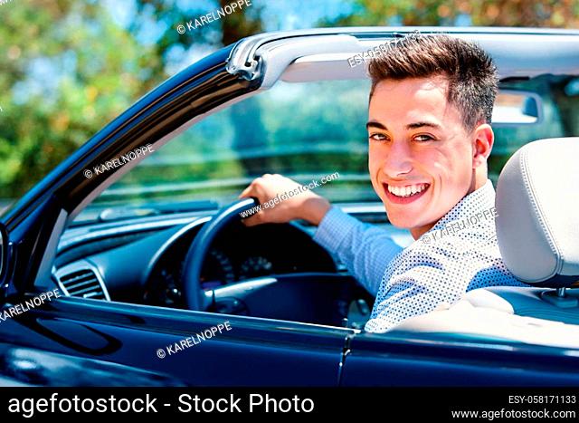 Portrait of attractive teen sitting in car. Young man sitting in convertible in driver seat