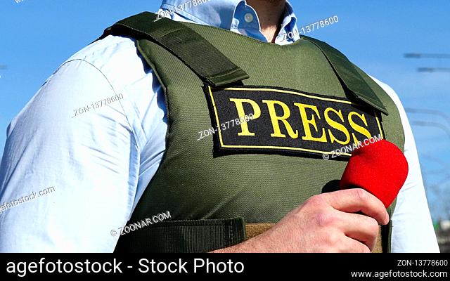 Hand with a microphone on the background of a bulletproof vest with press sign