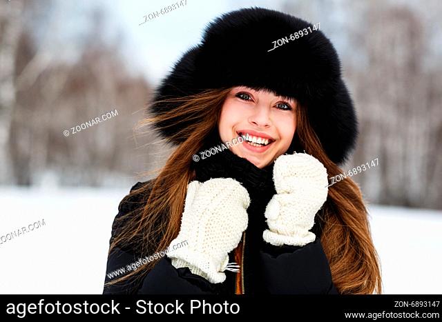 Portrait of beautiful smiling young woman in luxurious fur head cloth outdoor in winter
