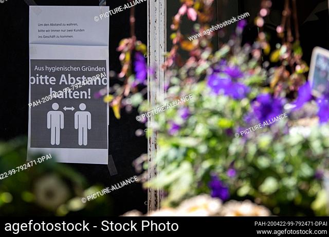 22 April 2020, Brandenburg, Potsdam: A sign in front of a flower shop in the city centre warns people to keep their distance